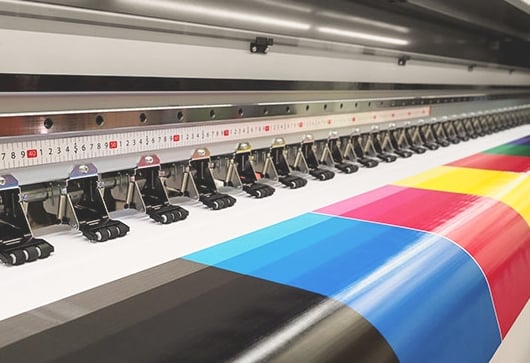 Digital storformatsskrivare som skriver ut en flerf&auml;rgad design p&aring; en presenning.